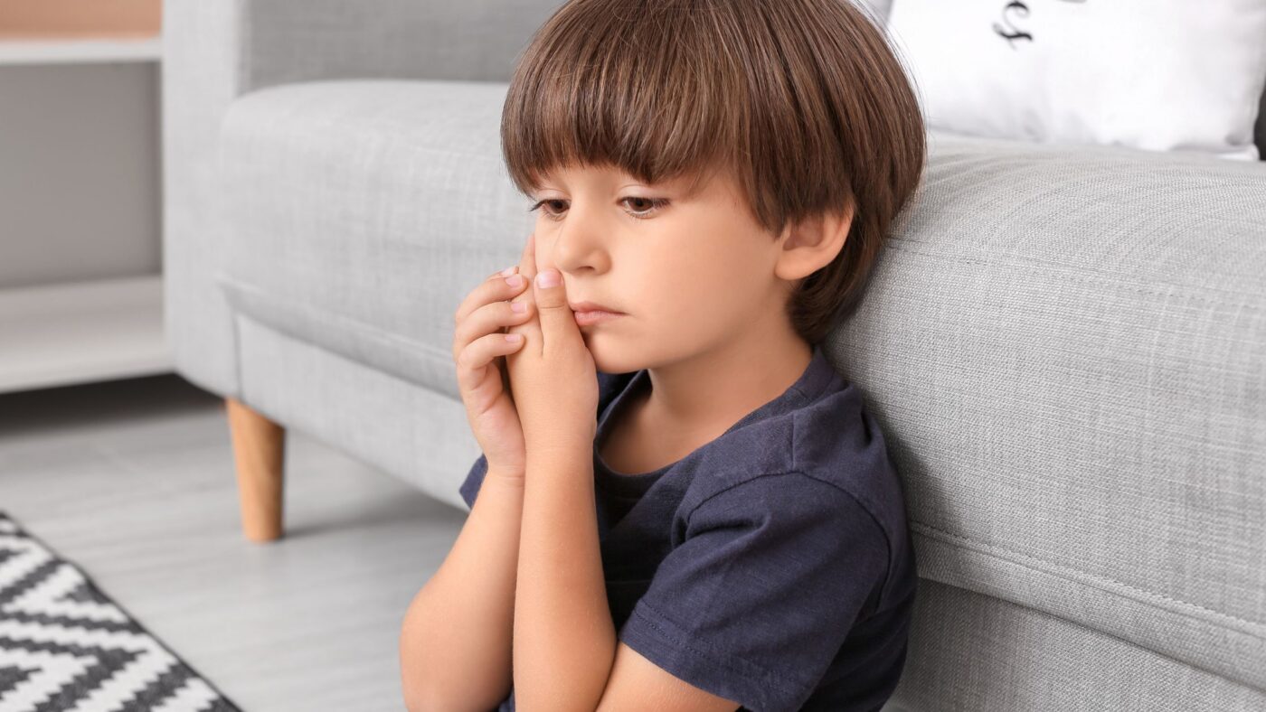 Shows an image of a boy clutching his jaw because he is experiencing pain.