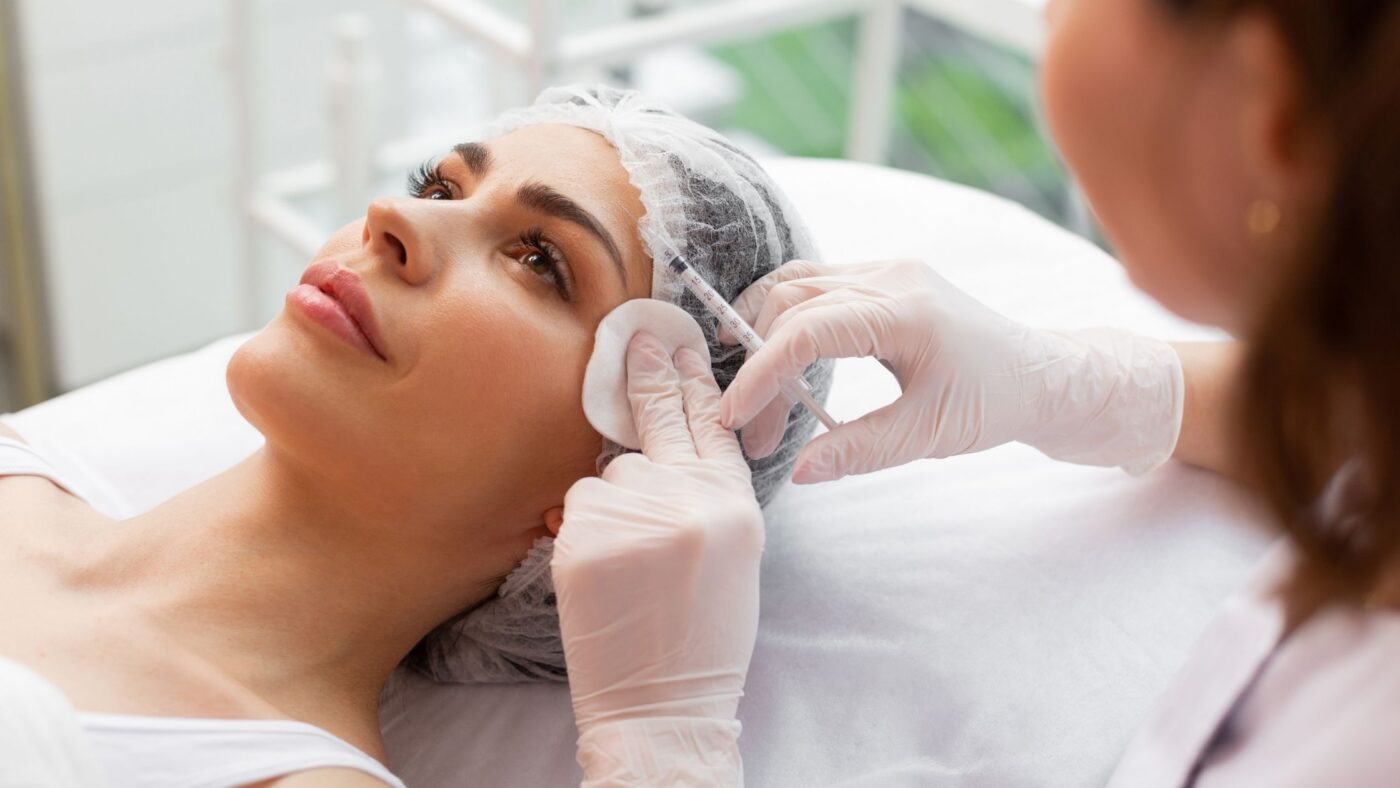 A clinician giving a patient a Botox injection in the forehead