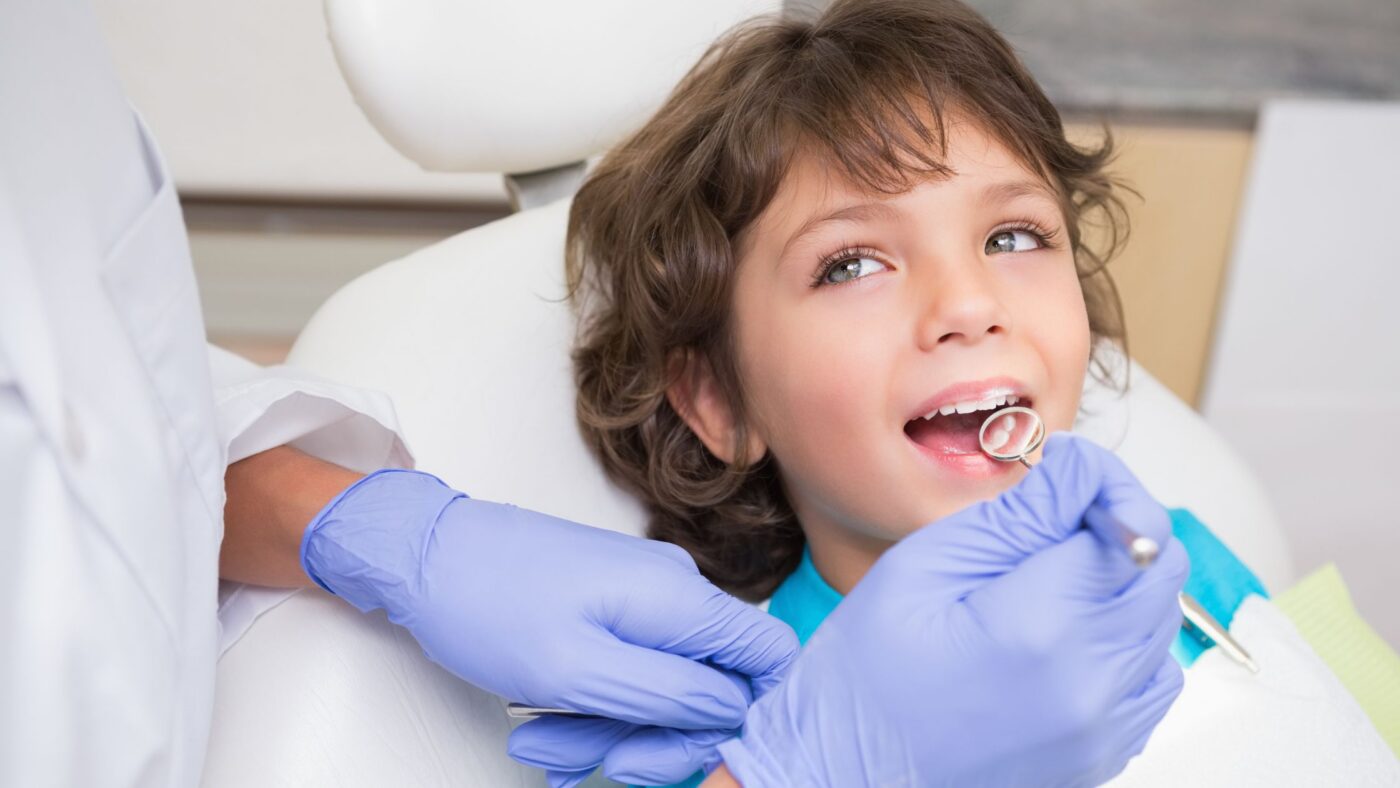 A boy looking up at the pediatric dentist during a check-up